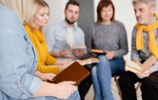 Gruppe Frauen und Männer sitzen im Halbkreis und besprechen sich