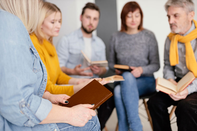 Gruppe Frauen und Männer sitzen im Halbkreis und besprechen sich